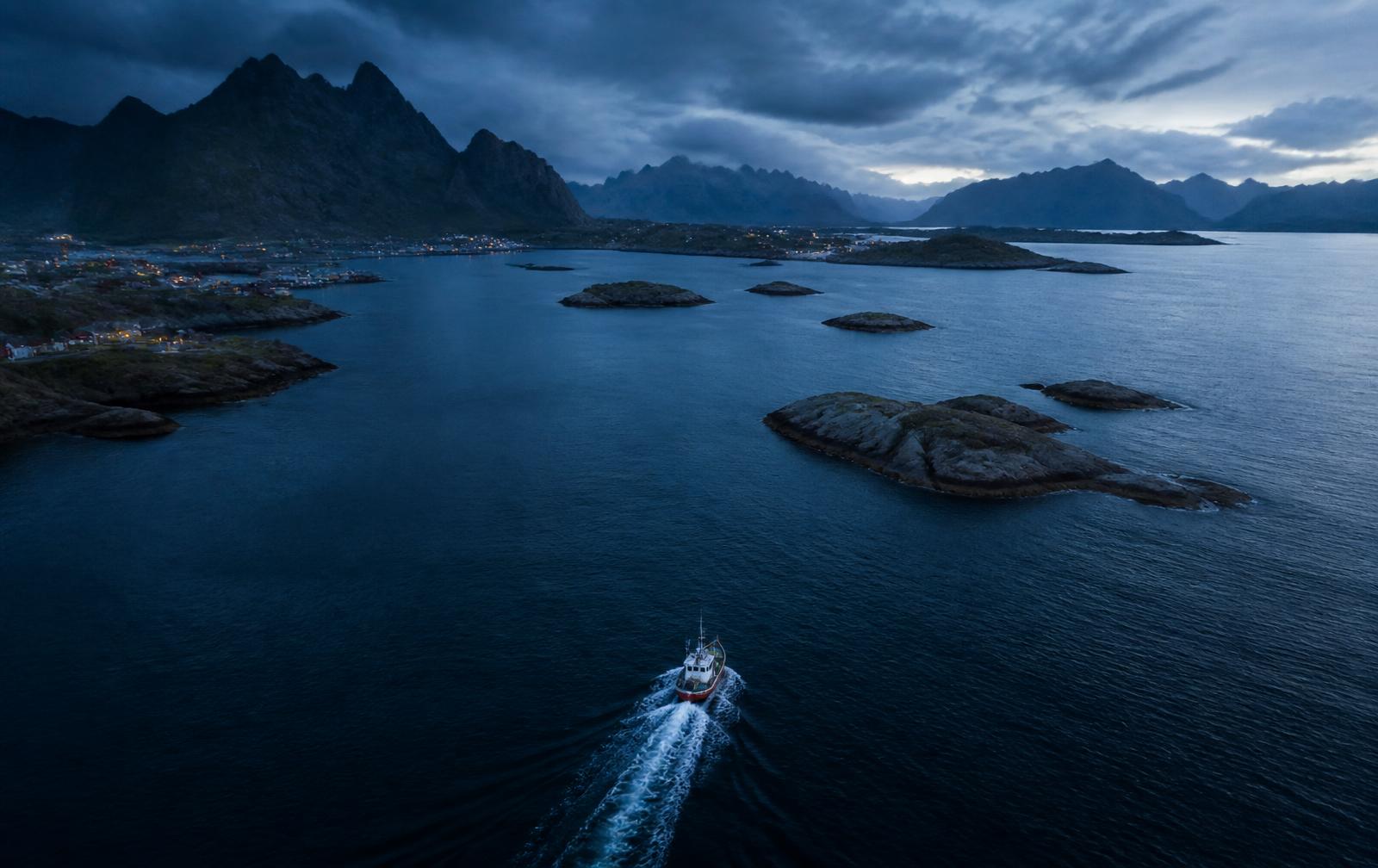 Norsk fjord i blåtimen med en liten fiskebåt